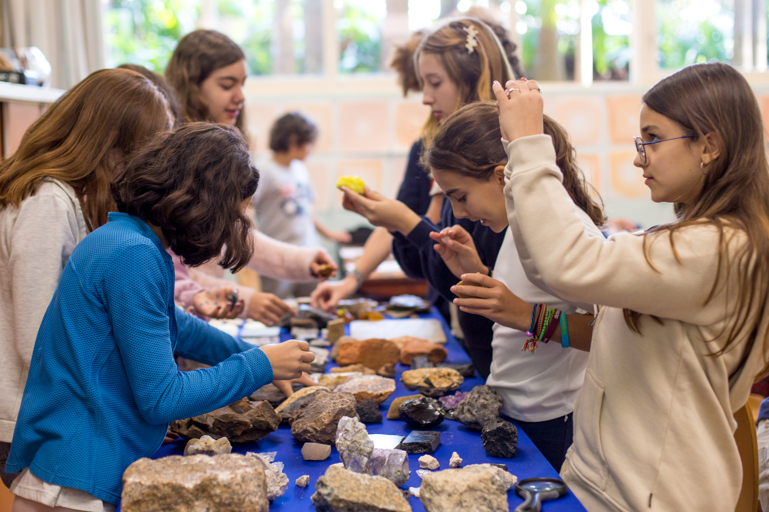 Adolescentes observando e manuseando rochas e minerais em aula geologia