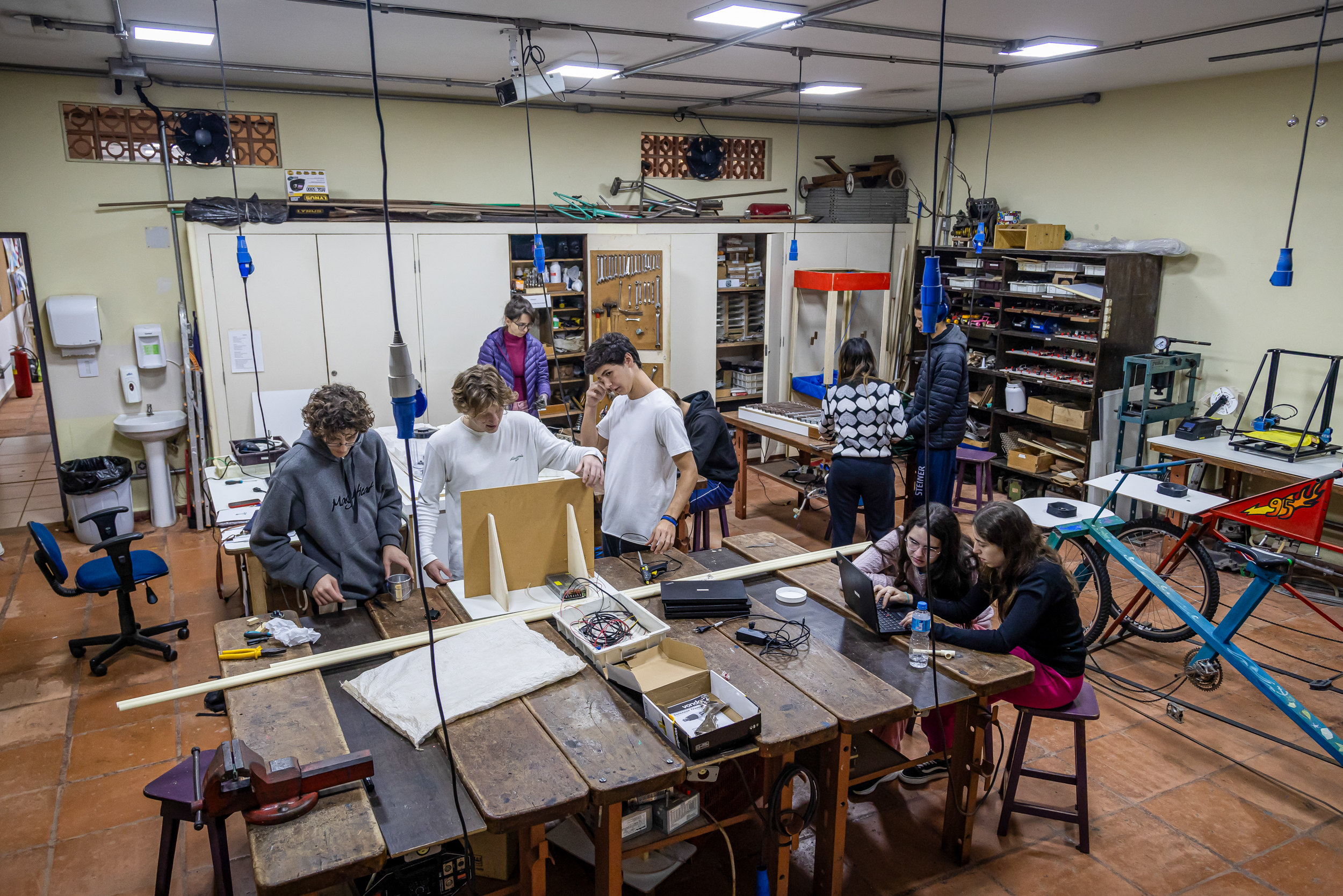 Alunos trabalhando em oficina com marcenaria e eletrônica na Escola Waldorf Rudolf Steiner, desenvolvendo projetos.