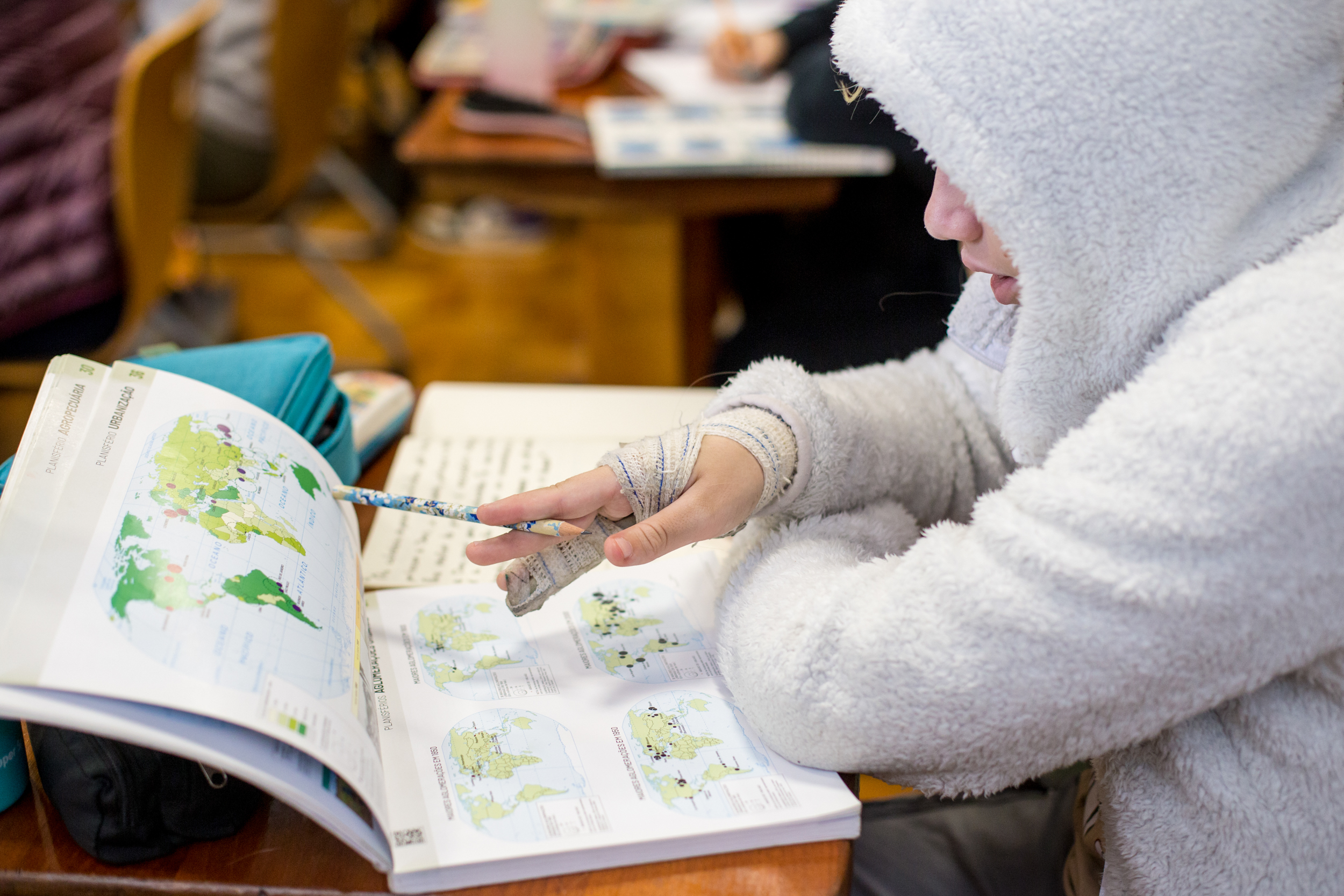 Aluna concentrada estudando mapa-múndi em livro de geografia na Escola Waldorf Rudolf Steiner.