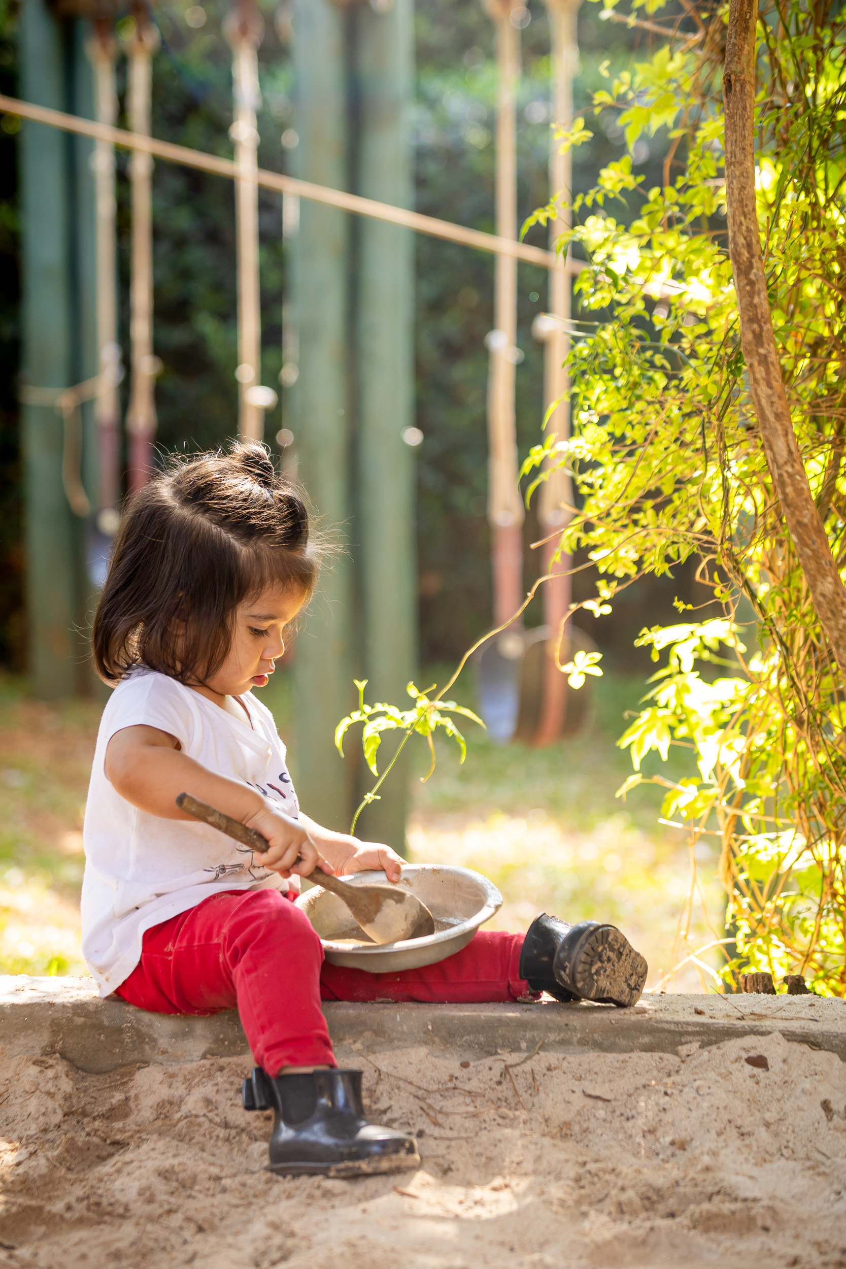 Criança pequena brincando com pá e tigela na areia ao ar livre