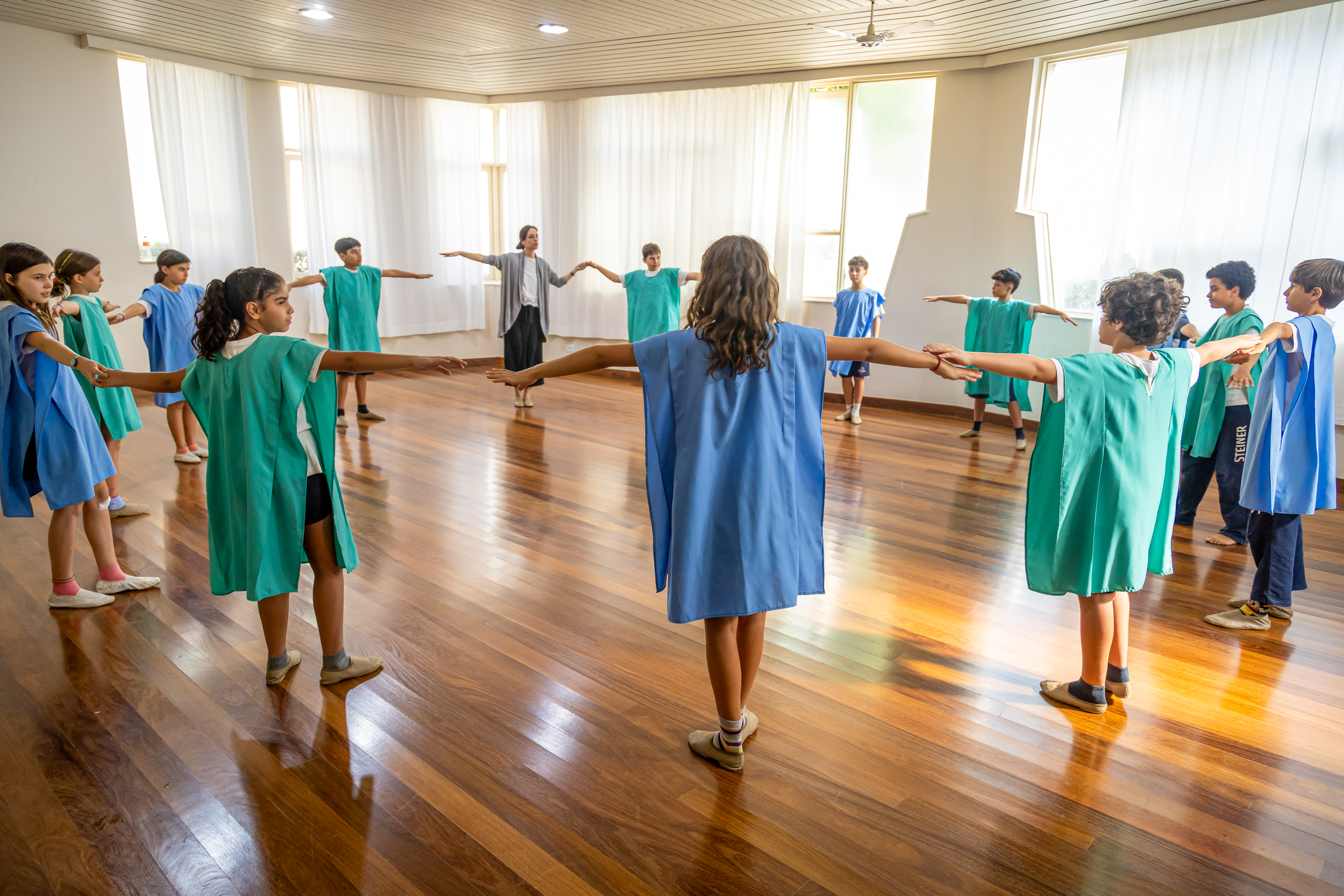 Grupo de alunos em aula de euritmia ou movimento, formando um círculo, na Escola Waldorf Rudolf Steiner.