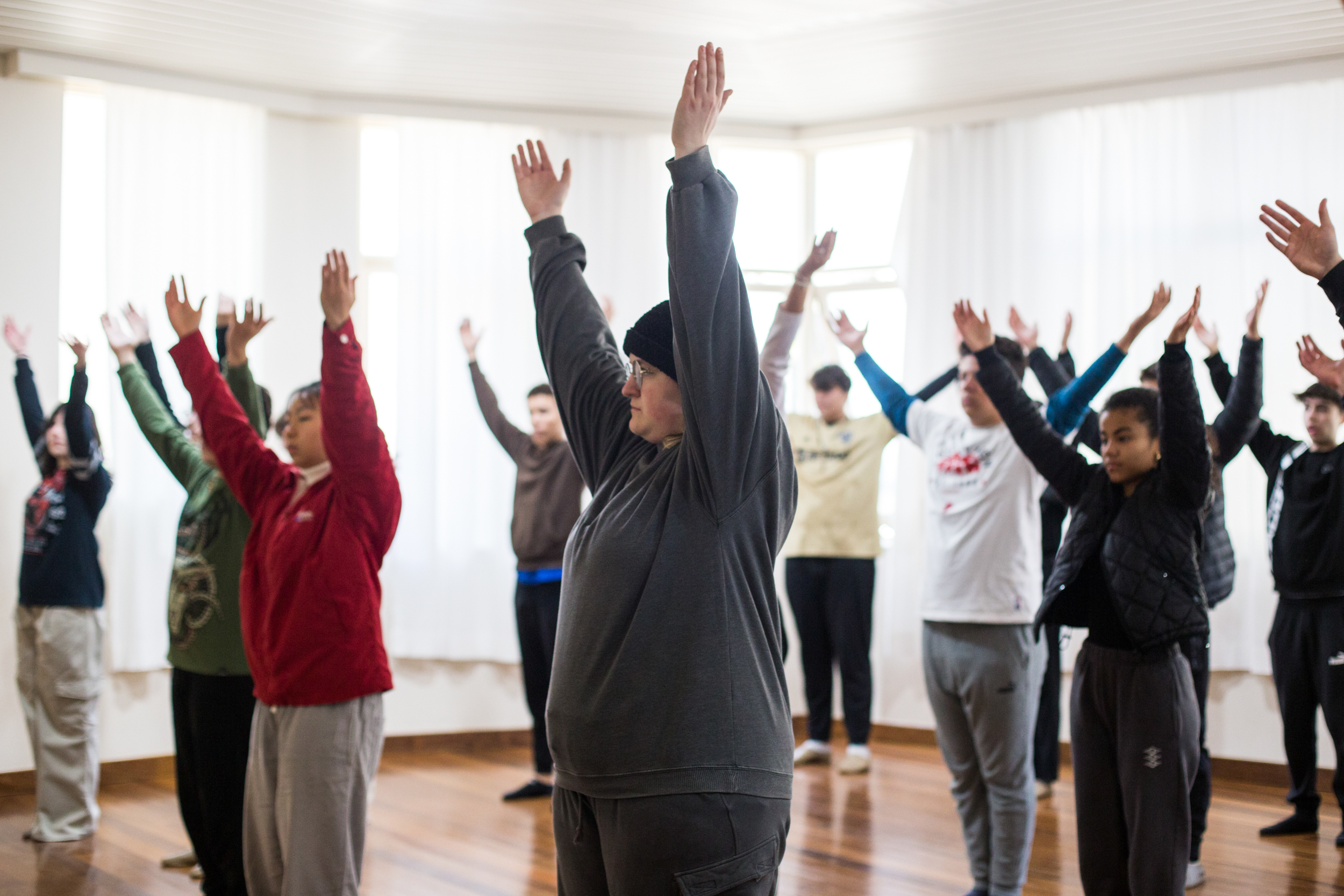 Jovens em aula de euritmia ou movimento com os braços levantados na Escola Waldorf Rudolf Steiner.
