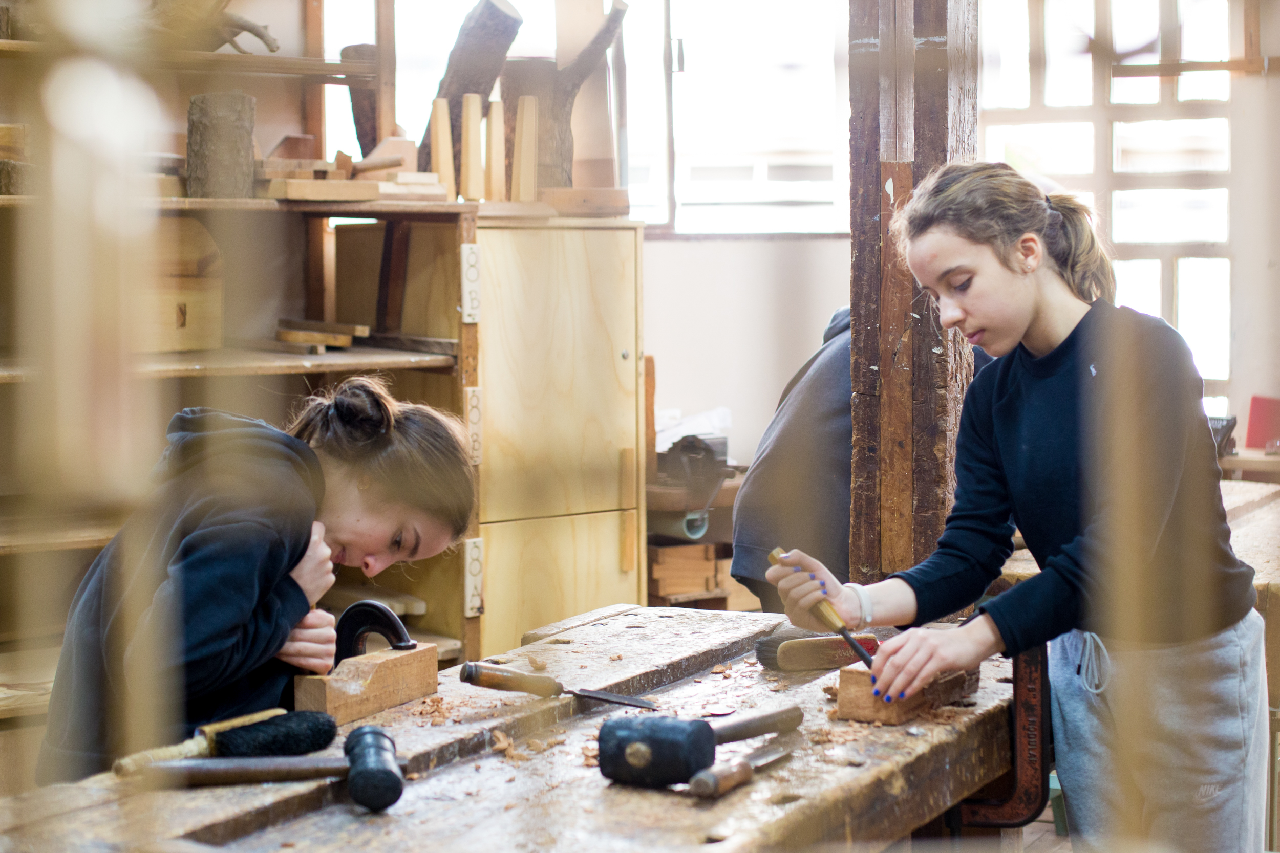 Duas adolescentes na oficina de marcenaria da Escola Waldorf Rudolf Steiner, realizando trabalhos manuais com madeira.