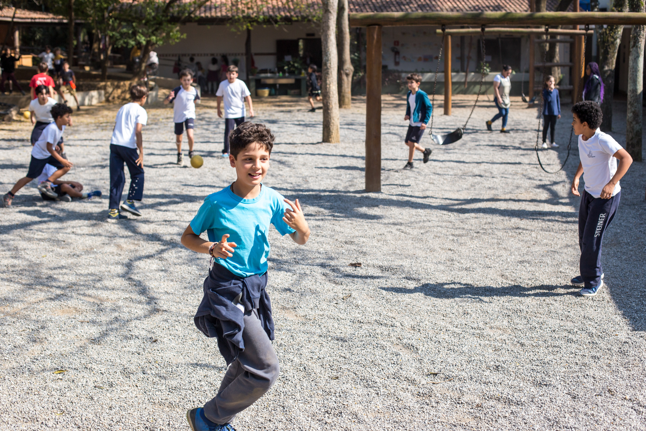 Alunos brincando e correndo no pátio da Escola Waldorf Rudolf Steiner durante o recreio.
