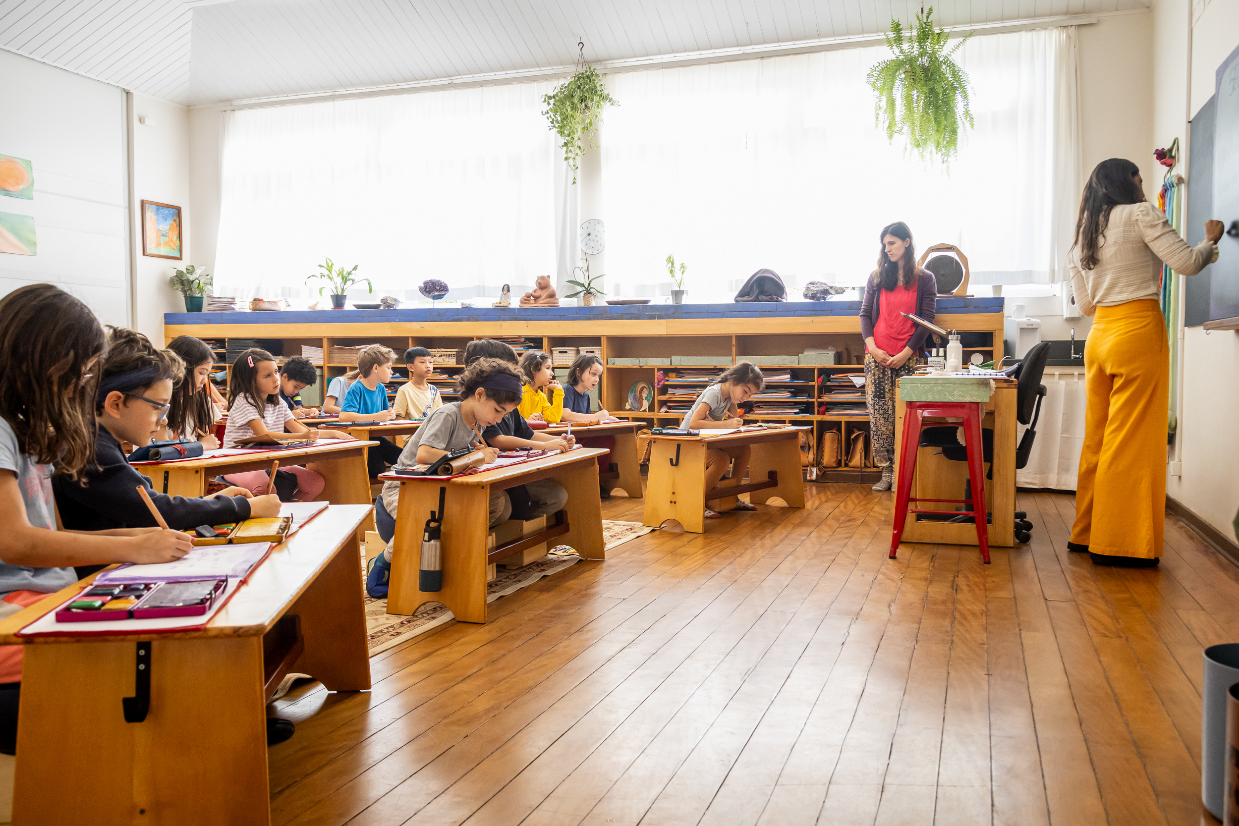 Crianças e professoras em sala de aula de ensino fundamental com luz natural